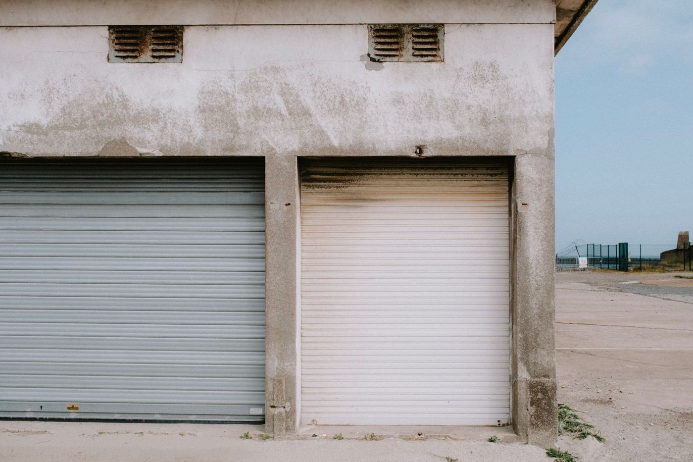 A row of weathered commercial roll-up doors on a metal building